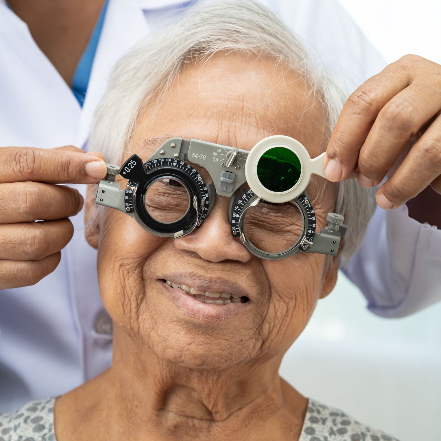 Elderly woman with optometric device over her eyes, being h